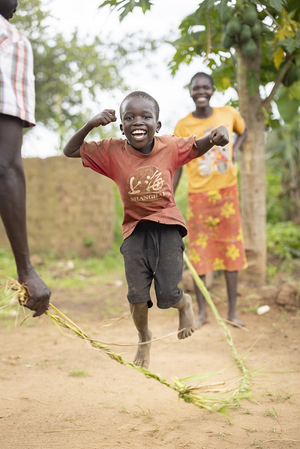 A boy jumps rope in Uganda, smiling.