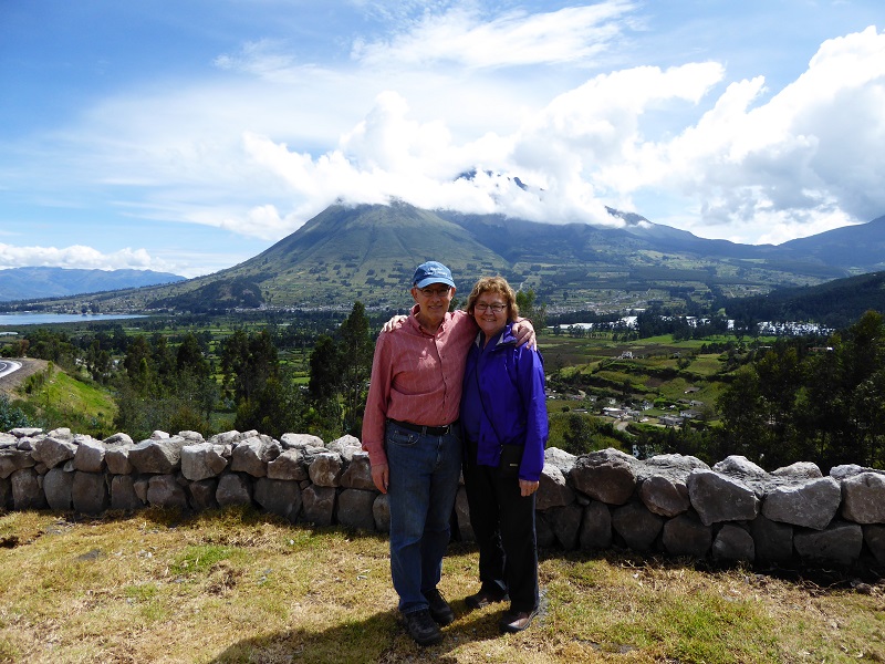 Man and woman stand in front of a mountain in Ecuador, smiling at the camera.