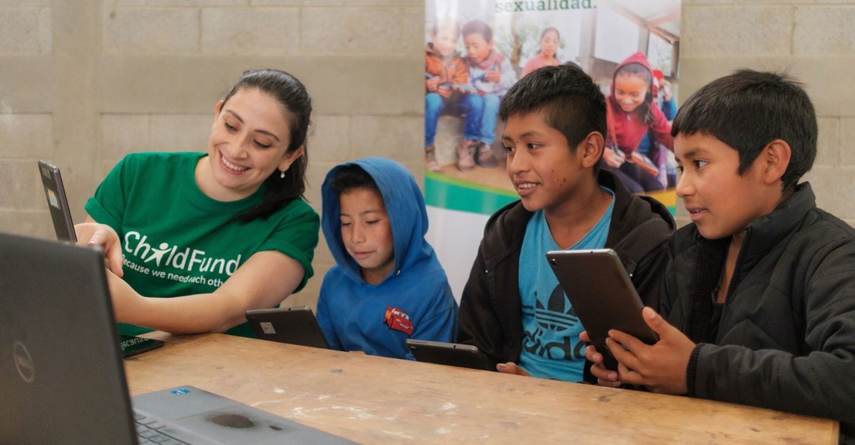  group of children in Guatemala sit at a table with tablets, learning about prevention of online sexual abuse