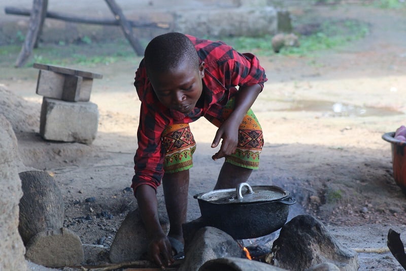 Boy cooks sweet potatoes over an open fire in Sierra Leone.