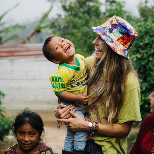 A woman holds a small boy in Guatemala, who is looking at the camera and smiling.