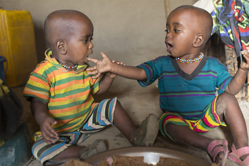 Two young girls sit indoors at home in Ethiopia, eating