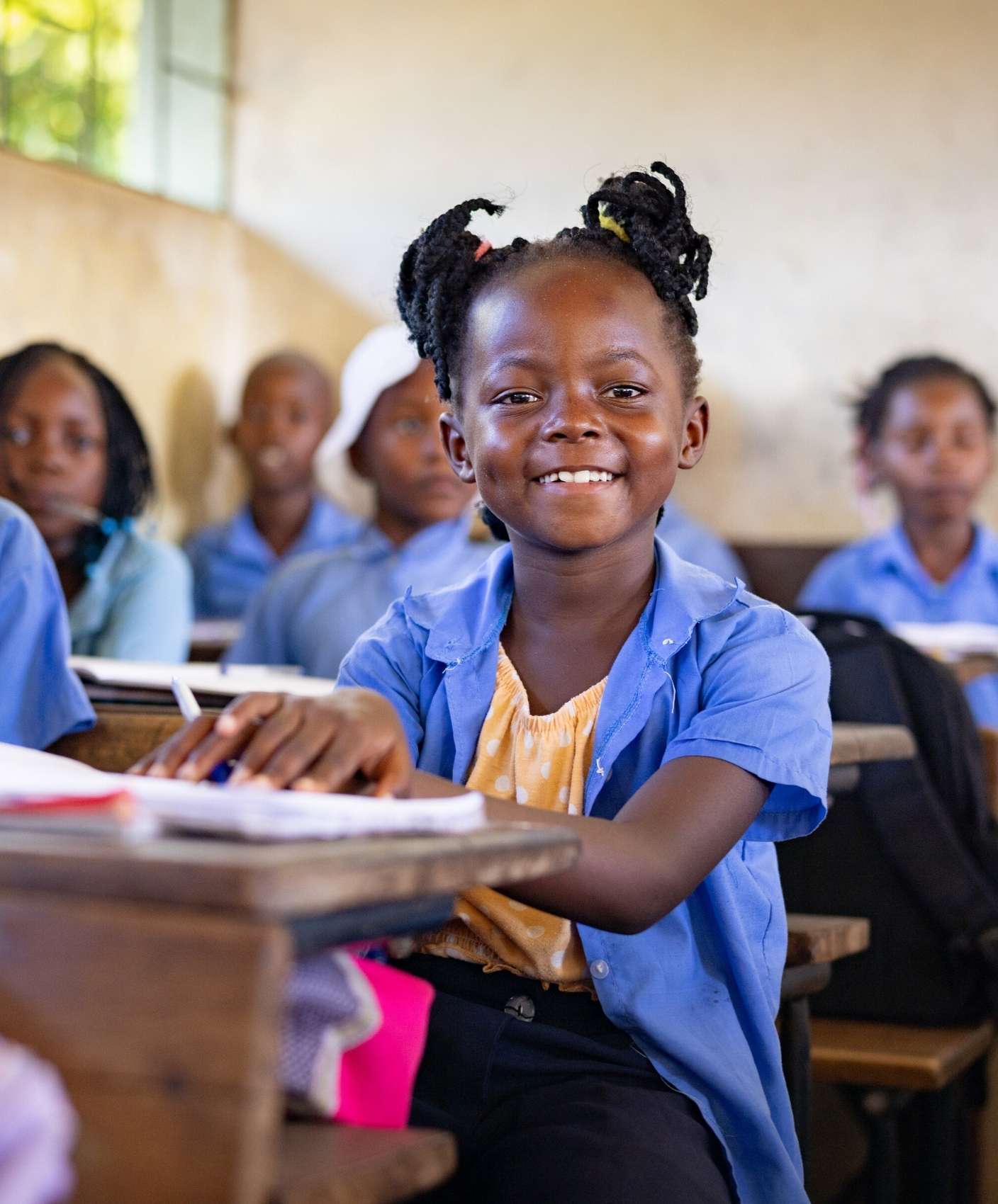 smiling girl sits at her desk in classroom