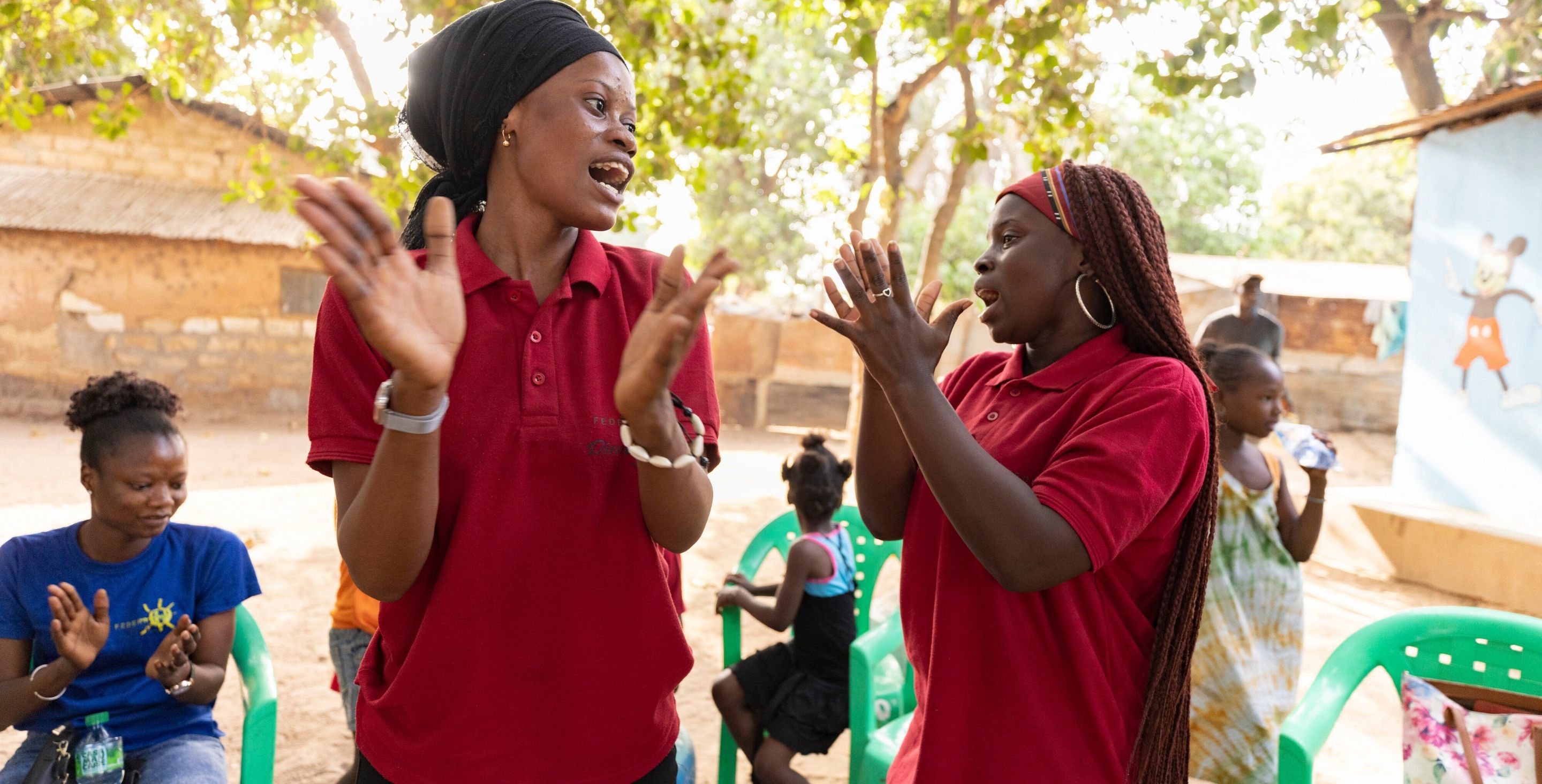 Young women in Senegal stand in a circle clapping their hands as part of a ChildFund youth club.