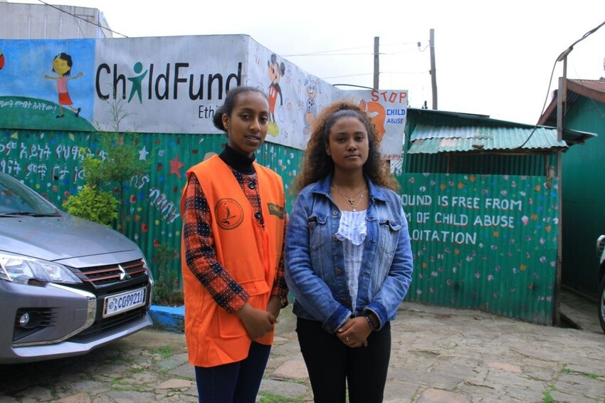 Two young women in Ethiopia stand shoulder to shoulder, looking seriously at the camera.