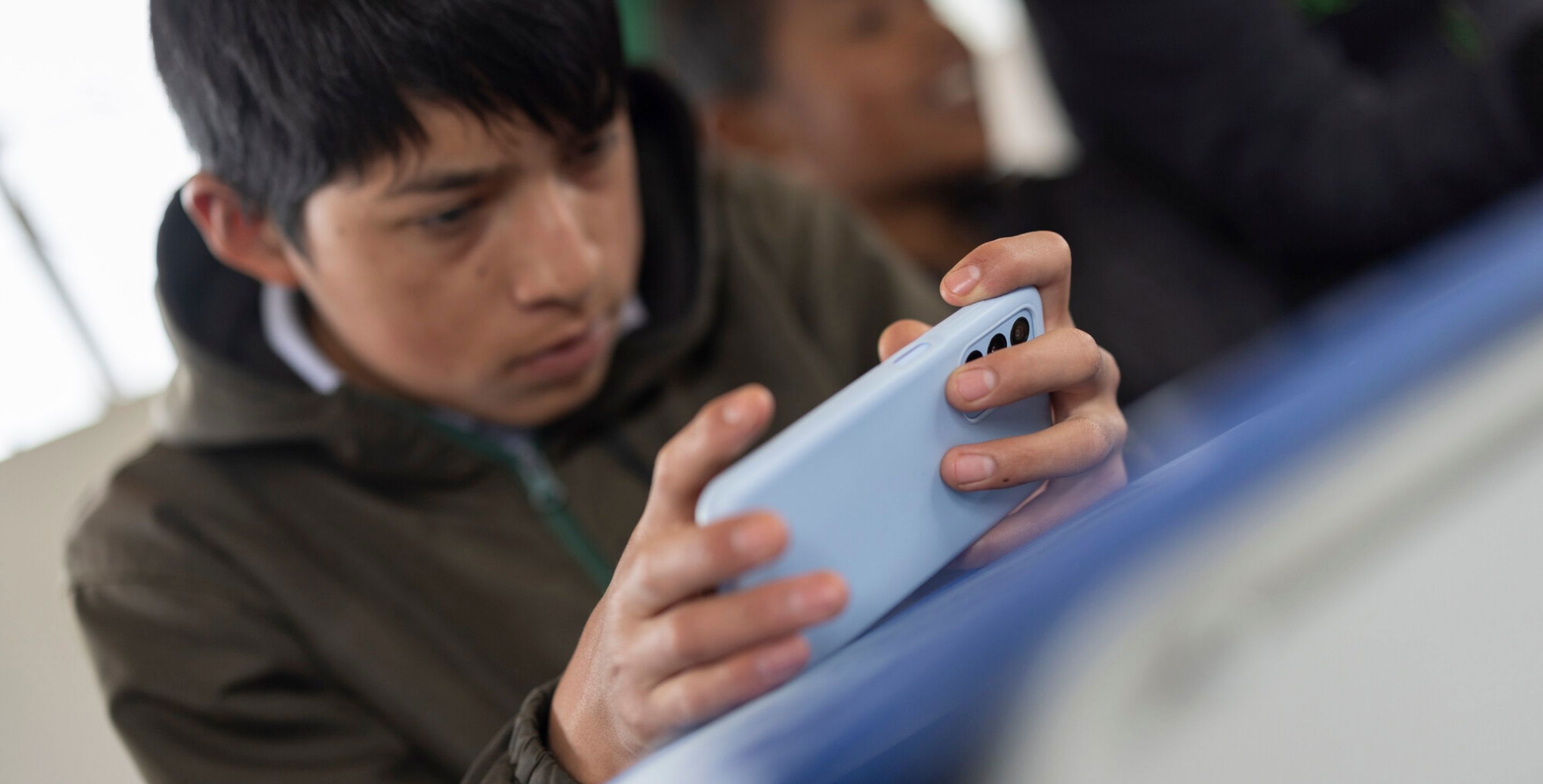 A teenage boy plays a game on a phone at his desk in Ecuador.