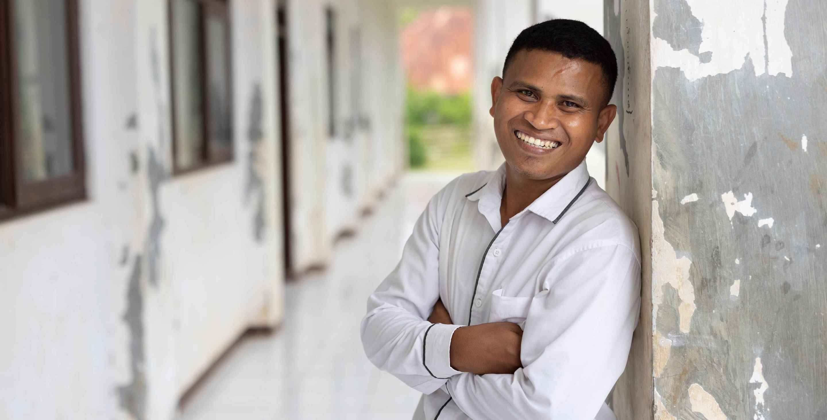 Young man leaning against a wall and smiling