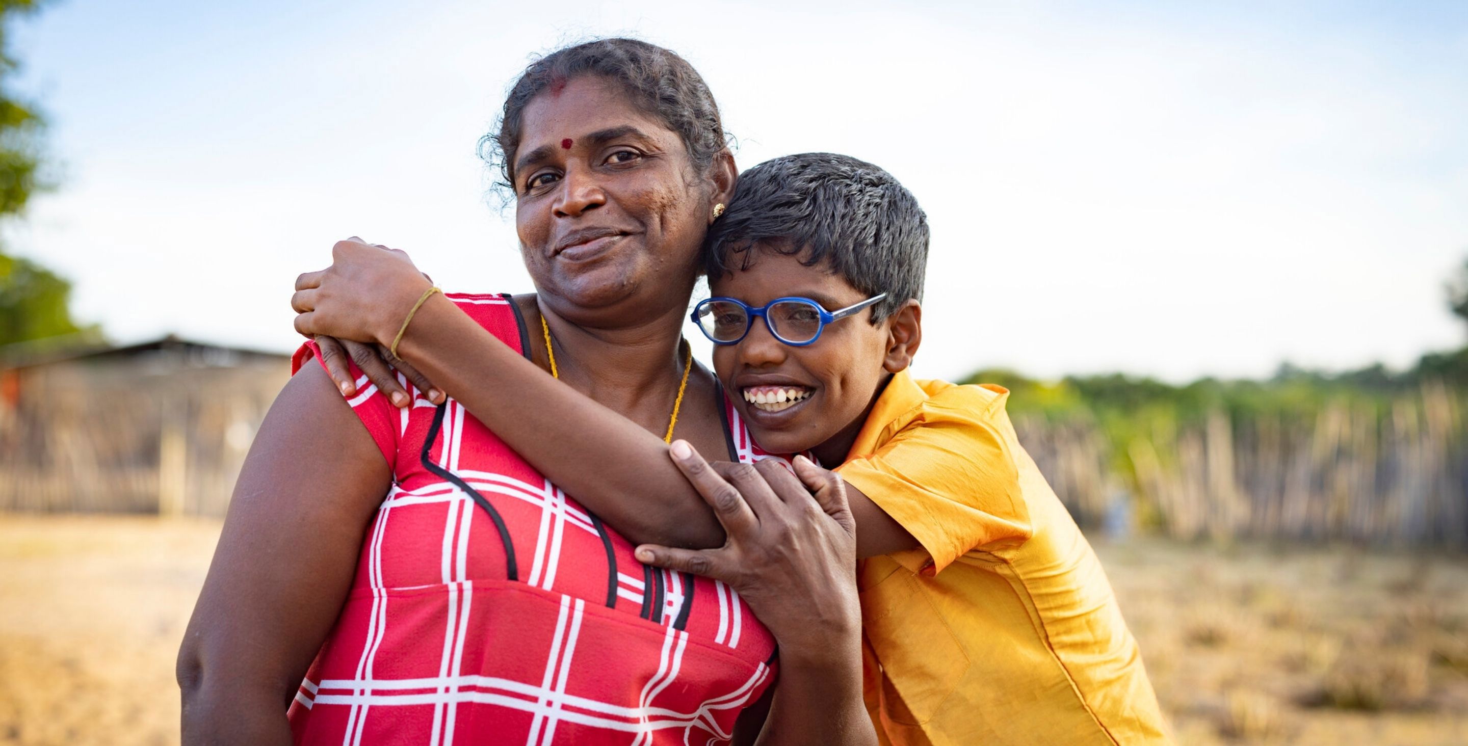 A mother and her teenage son in Sri Lanka smile at the camera. 