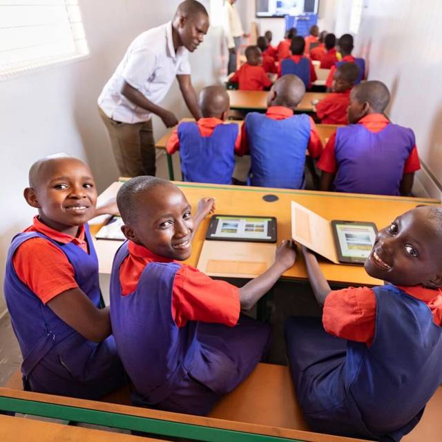 A group of girls wearing colorful uniforms sit at their desks.