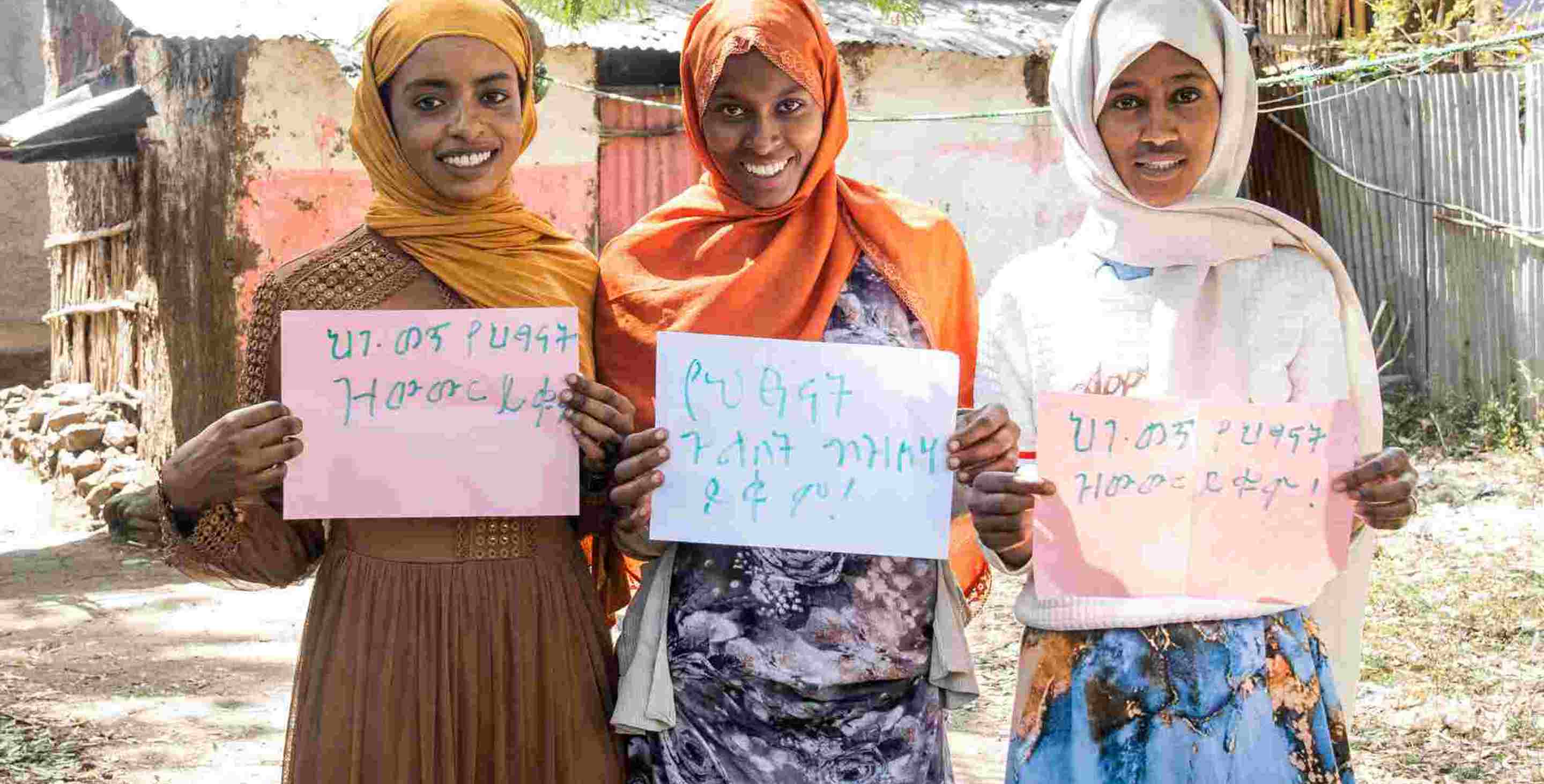 Three Ethiopian teenage girls holding signs saying 