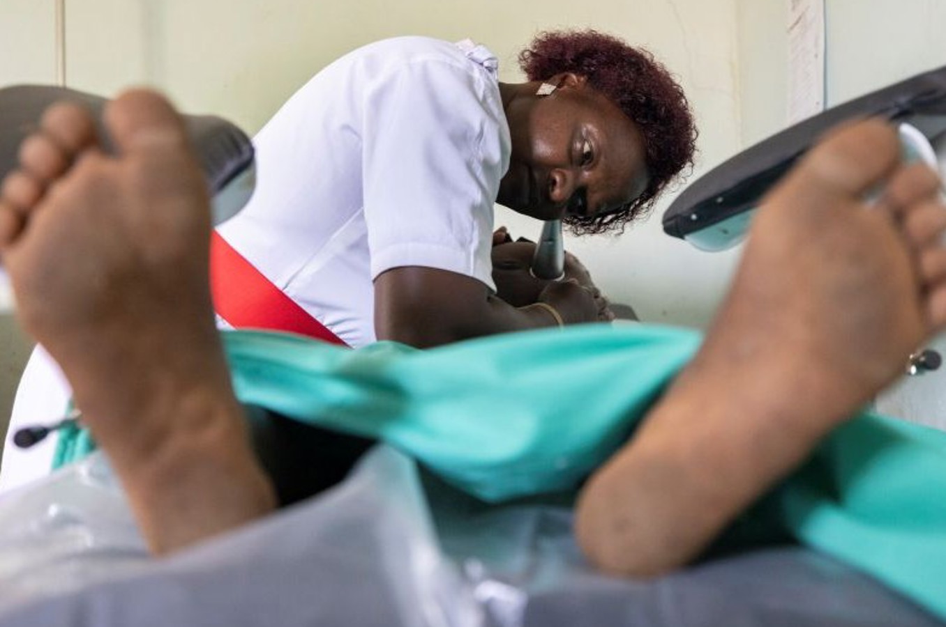An expectant mother lays on a bed in a delivery room.