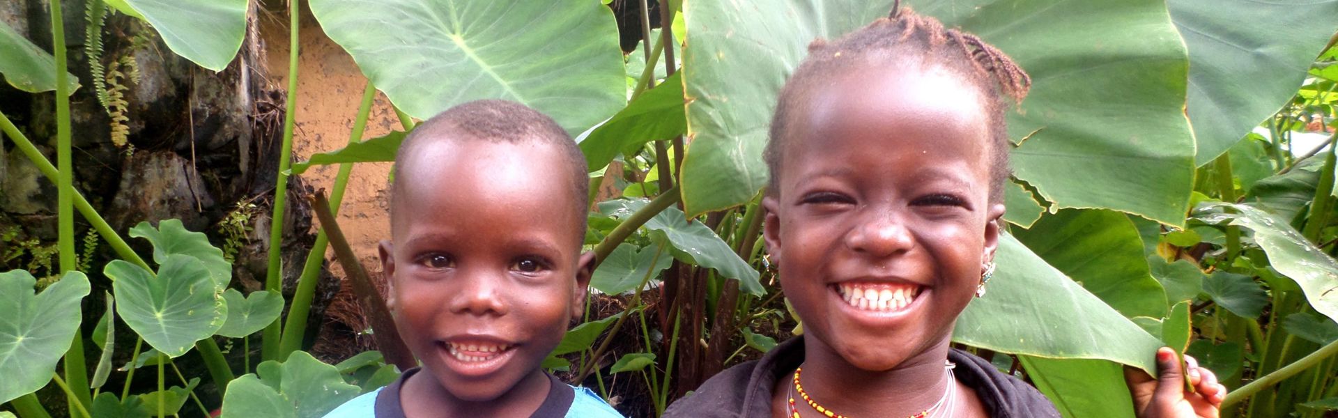 Two children in Guinea smile broadly at the camera.