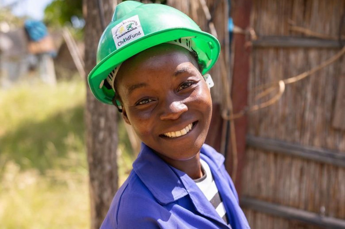 Youth in hard hat smiles outside while taking part in vocational training program