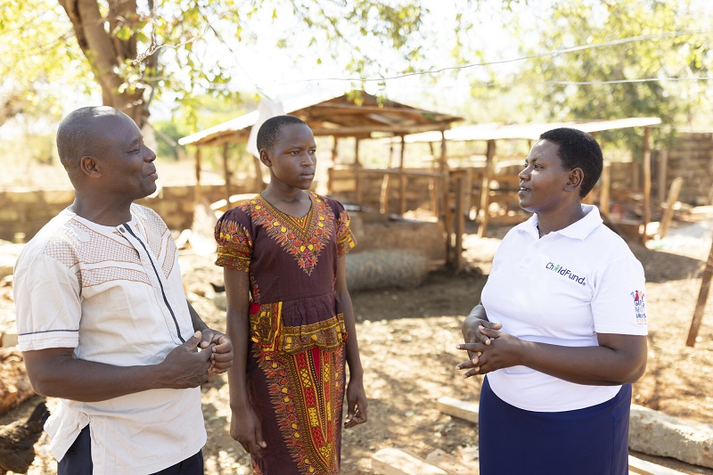 A ChildFund social worker and a local chief speak to a young girl in Kenya.