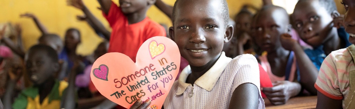 A young girl holds up a handwritten letter.