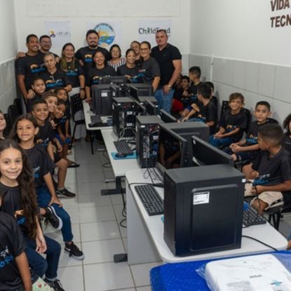 A group of children sit at computers at a computer lab in Brazil, with their teachers in the background.