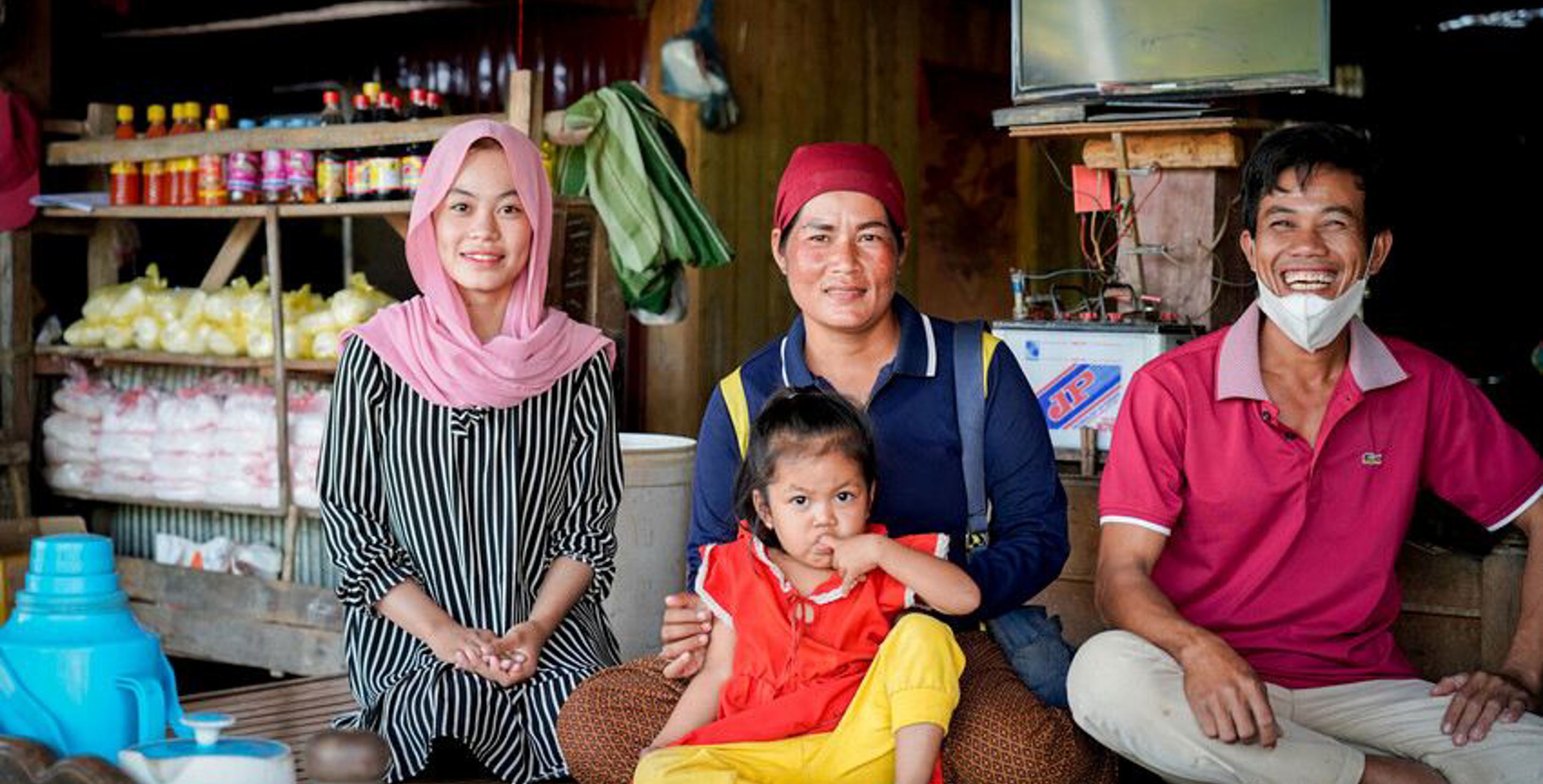 a mother, father and their two daughters sitting and smiling on a store porch