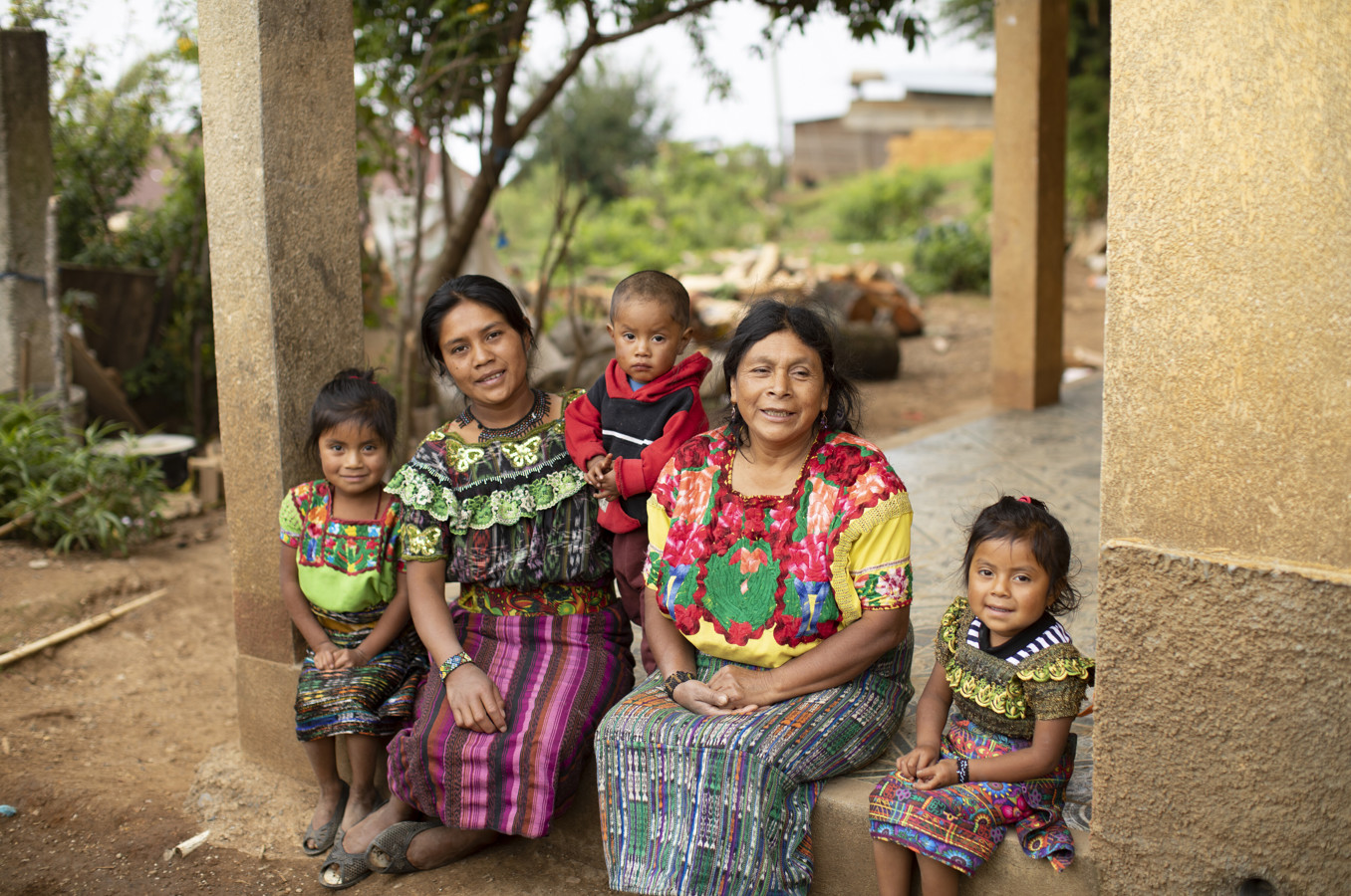 A family wearing traditional garb sits on their porch in Guatemala.