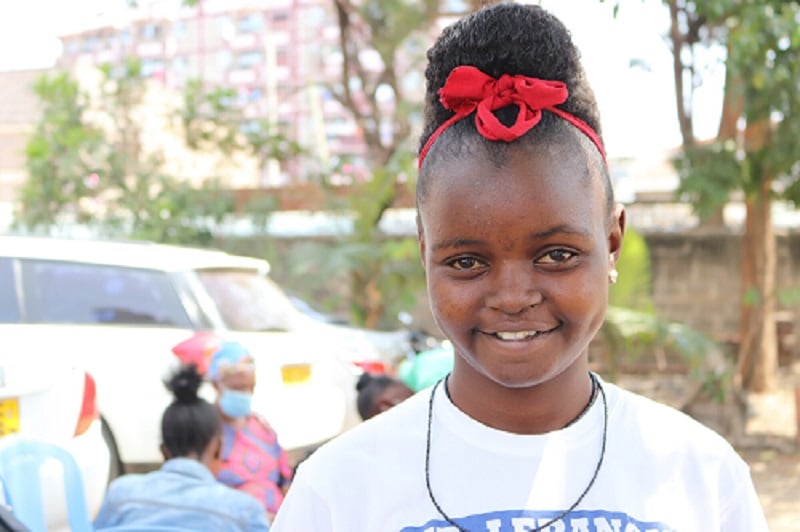 Teen girl from Kenya smiles at the camera.