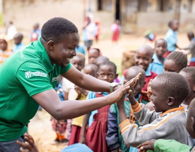 Man smiles and high fives group of children