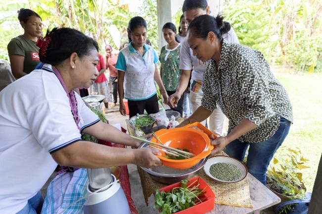 A woman hands out food on a table in an outdoor setting.