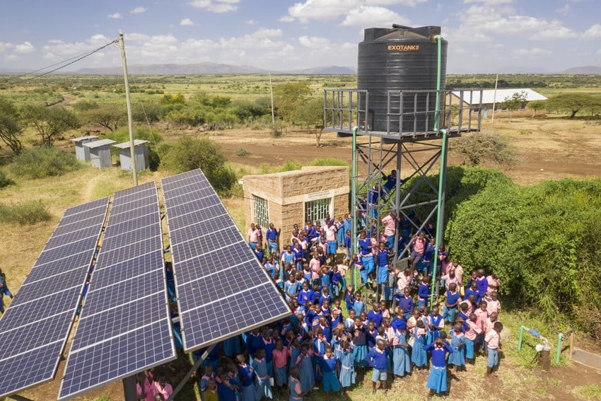 Drone photo of schoolchildren gathering by a water pumping system in Kenya.