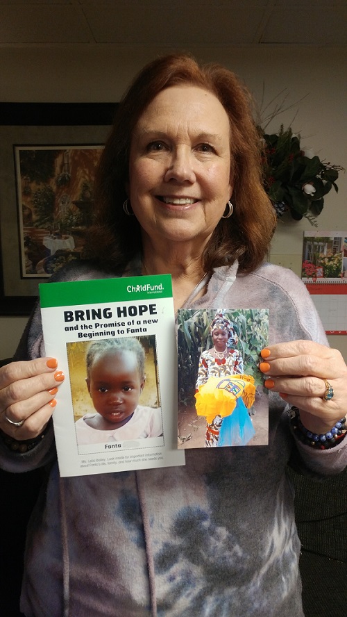 Woman holds up a photo of her sponsored child in Guinea