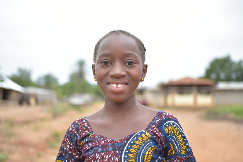 Young girl in Sierra Leone smiles at camera.