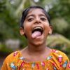A little girl in Sri Lanka sticks her tongue out in a silly gesture.