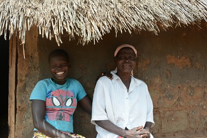 Teenage girl and elderly woman smiling outside in Uganda. 
