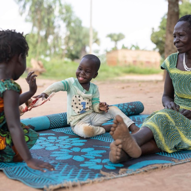 Helen, grandmother, plays outside with happy grandchildren