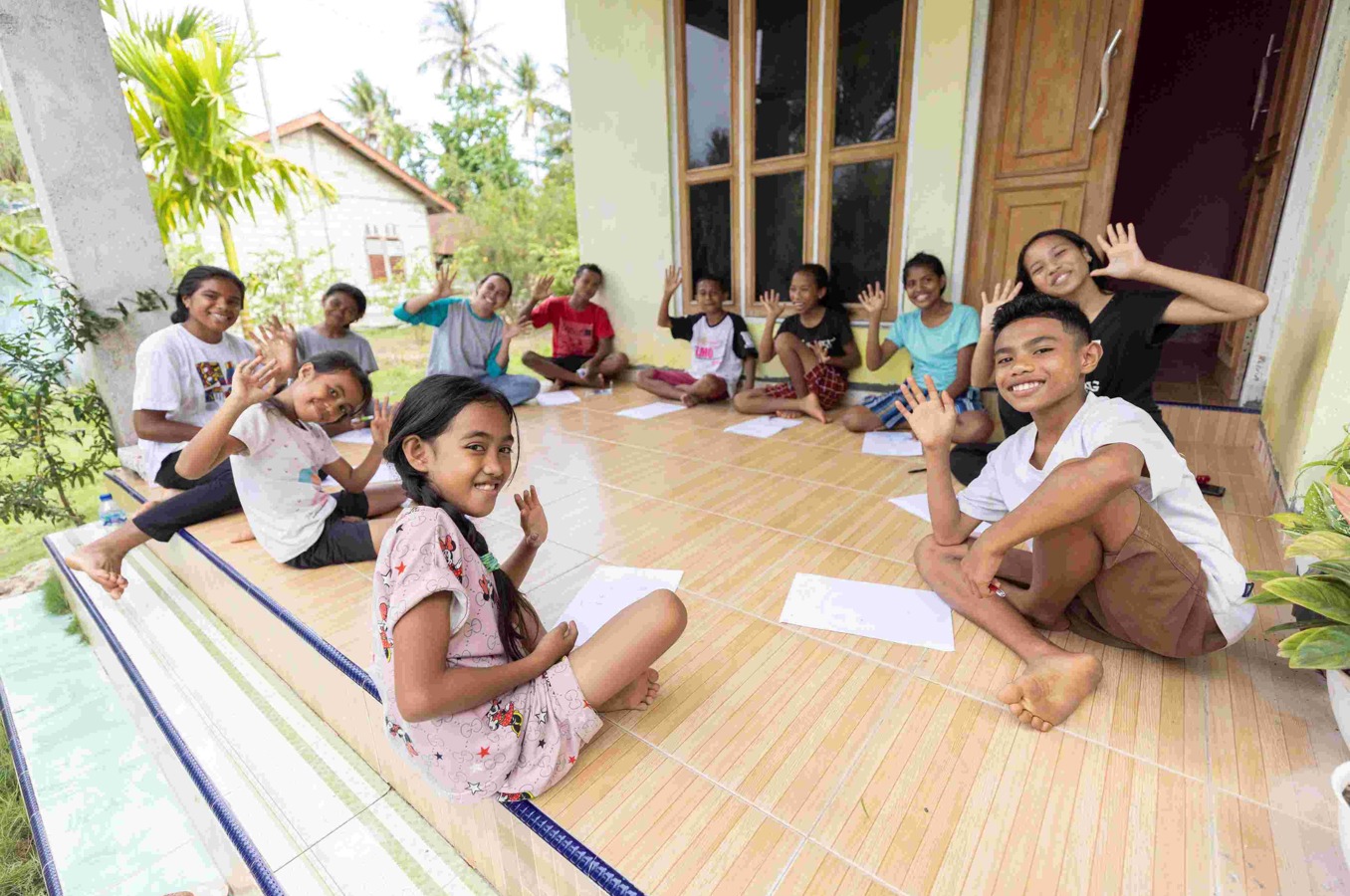 A group of children and youth participating in a ChildFund Youth Circle meeting on a porch in East Nusa Tenggara, Indonesia.