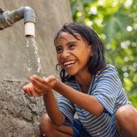 A girl in Indonesia washes her hands at a faucet