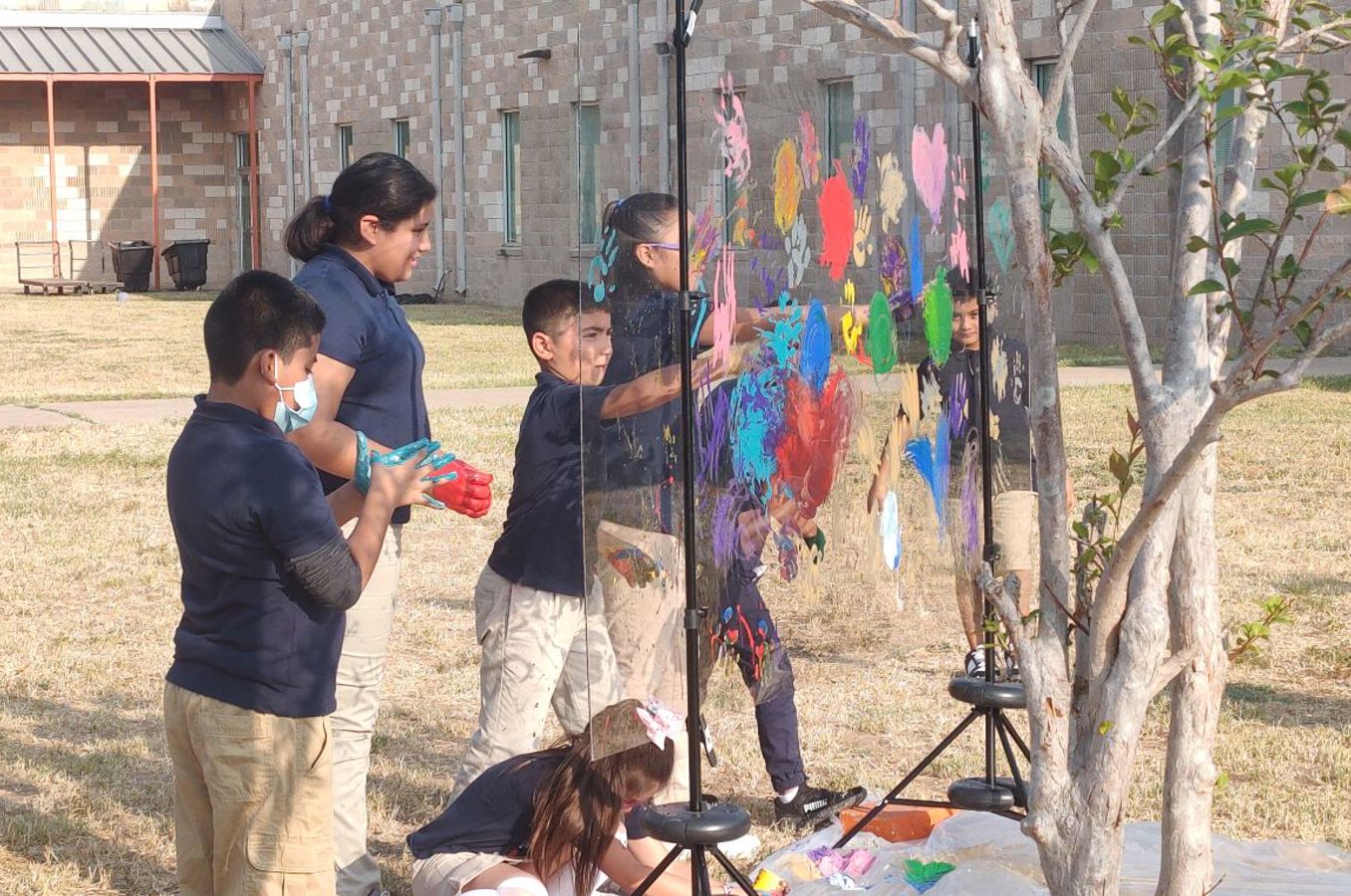 Children paint a backdrop outside as part of an art project.