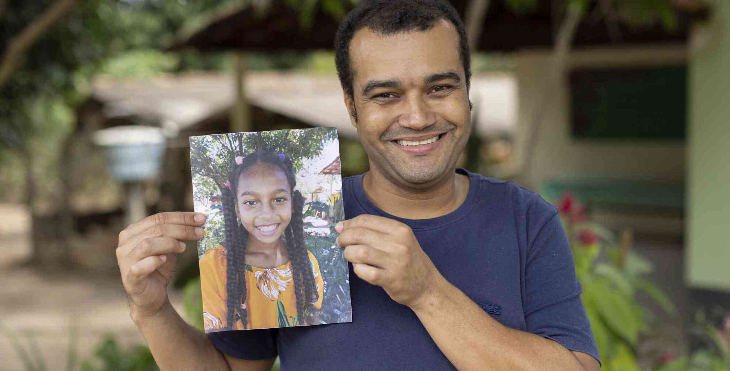 Claudio holds up a picture of his sponsored child.
