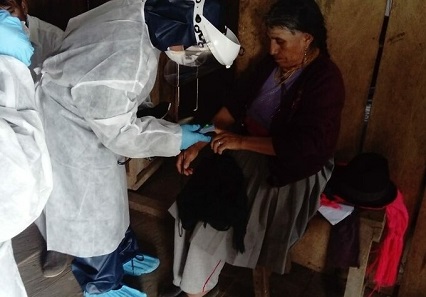 A woman in personal protective equipment helps a patient in Ecuador during COVID-19 pandemic.