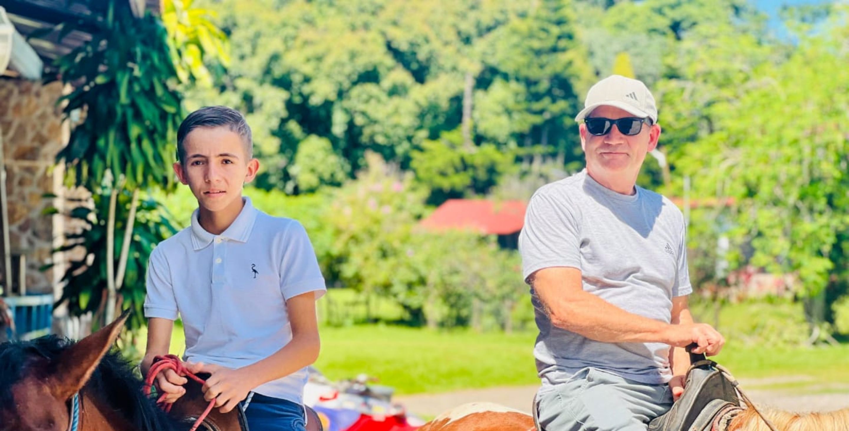 A man and a young boy ride horses together in Honduras.