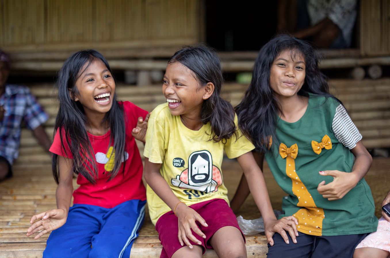 Three girls in Indonesia exchange glances while laughing.