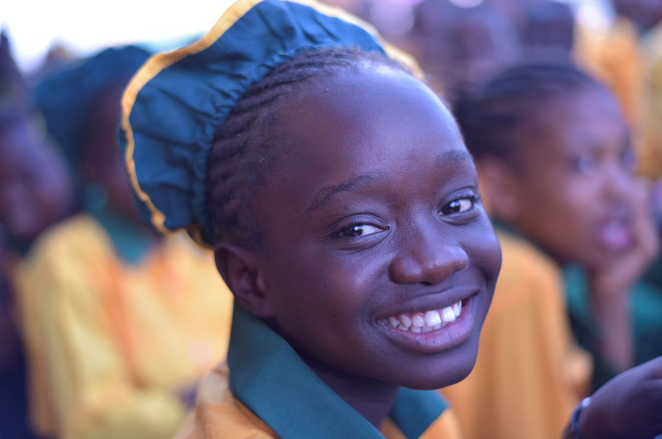 A girl in Sierra Leone wearing a school uniform smiles at the camera.