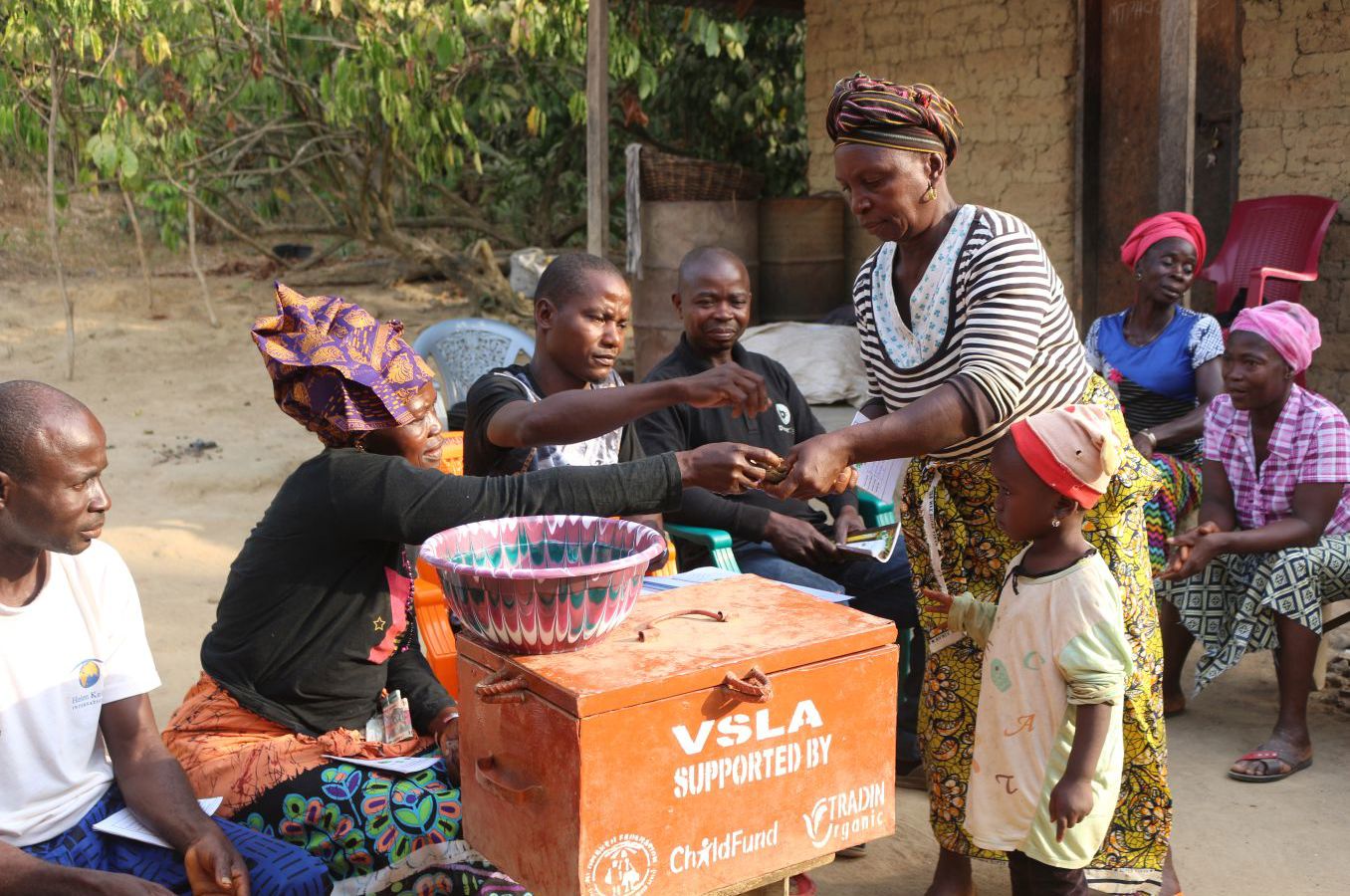 Women in Sierra Leone gather together in a circle to conduct a meeting of their Village Savings and Loan program.
