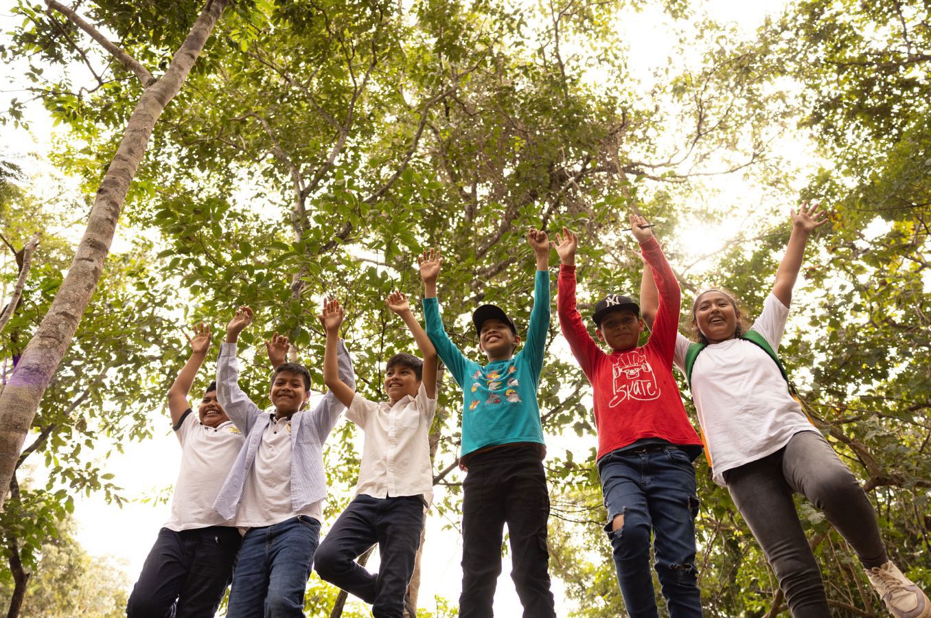 A group of children jump for joy in a forest in Bolivia.