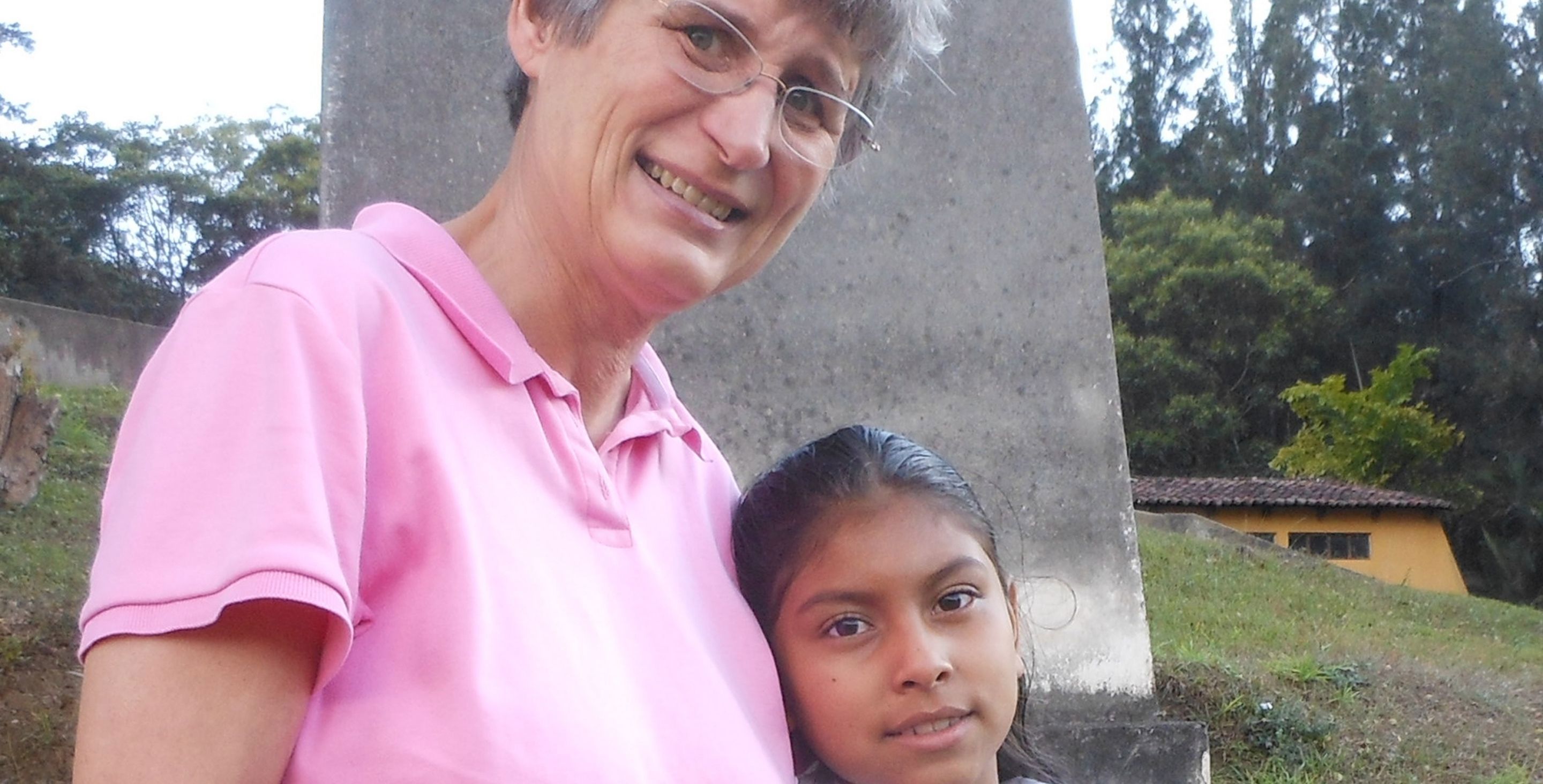A woman with short gray hair hugs a little girl in Guatemala.