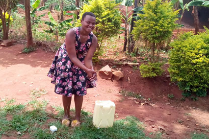 A teen girl from Uganda washes her hands outside. 