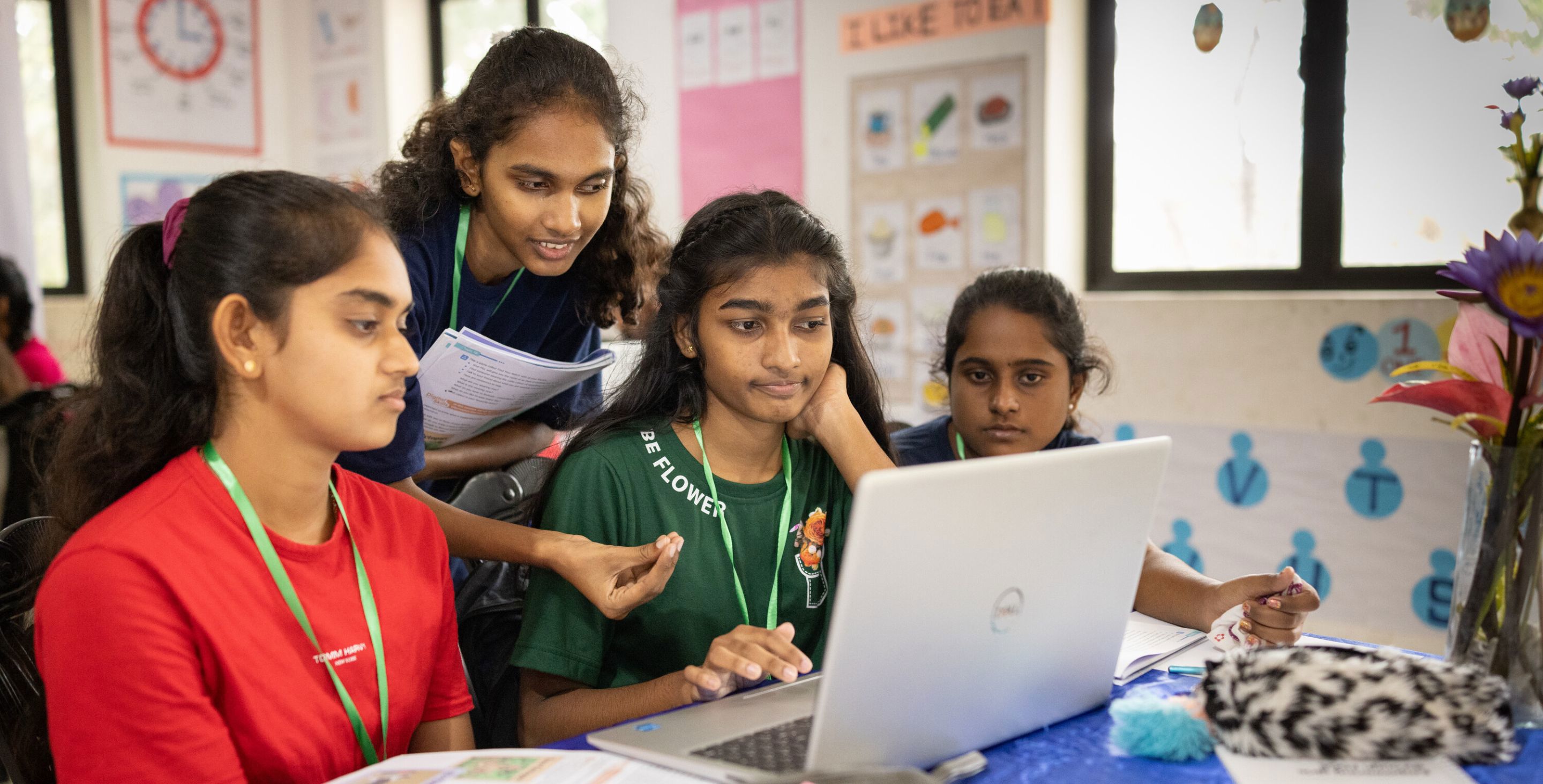 A group of girls in Sri Lanka gather around a computer, studying