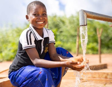 Child collecting clean water from a new community tap in rural Nampula Province, Mozambique.