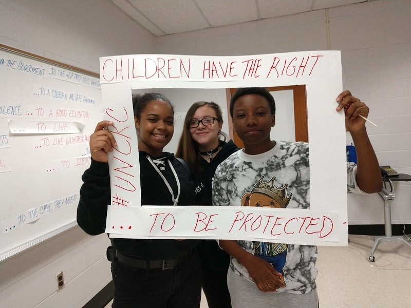 U.S. teens hold up a sign saying that children have the right to be protected.