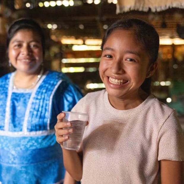 A young girl drinks a glass of clean water.