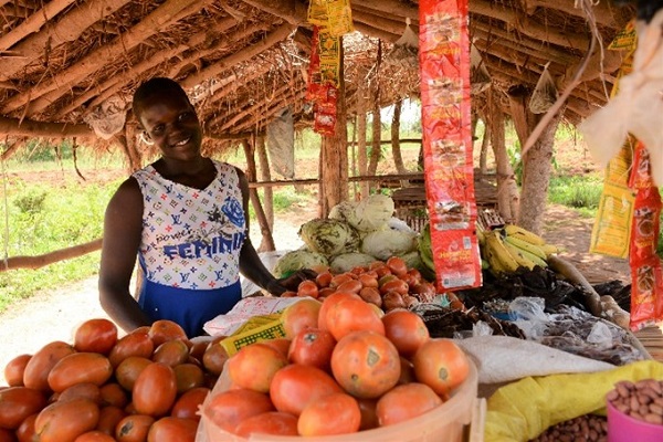 Girl smiles at a food stall in Uganda.