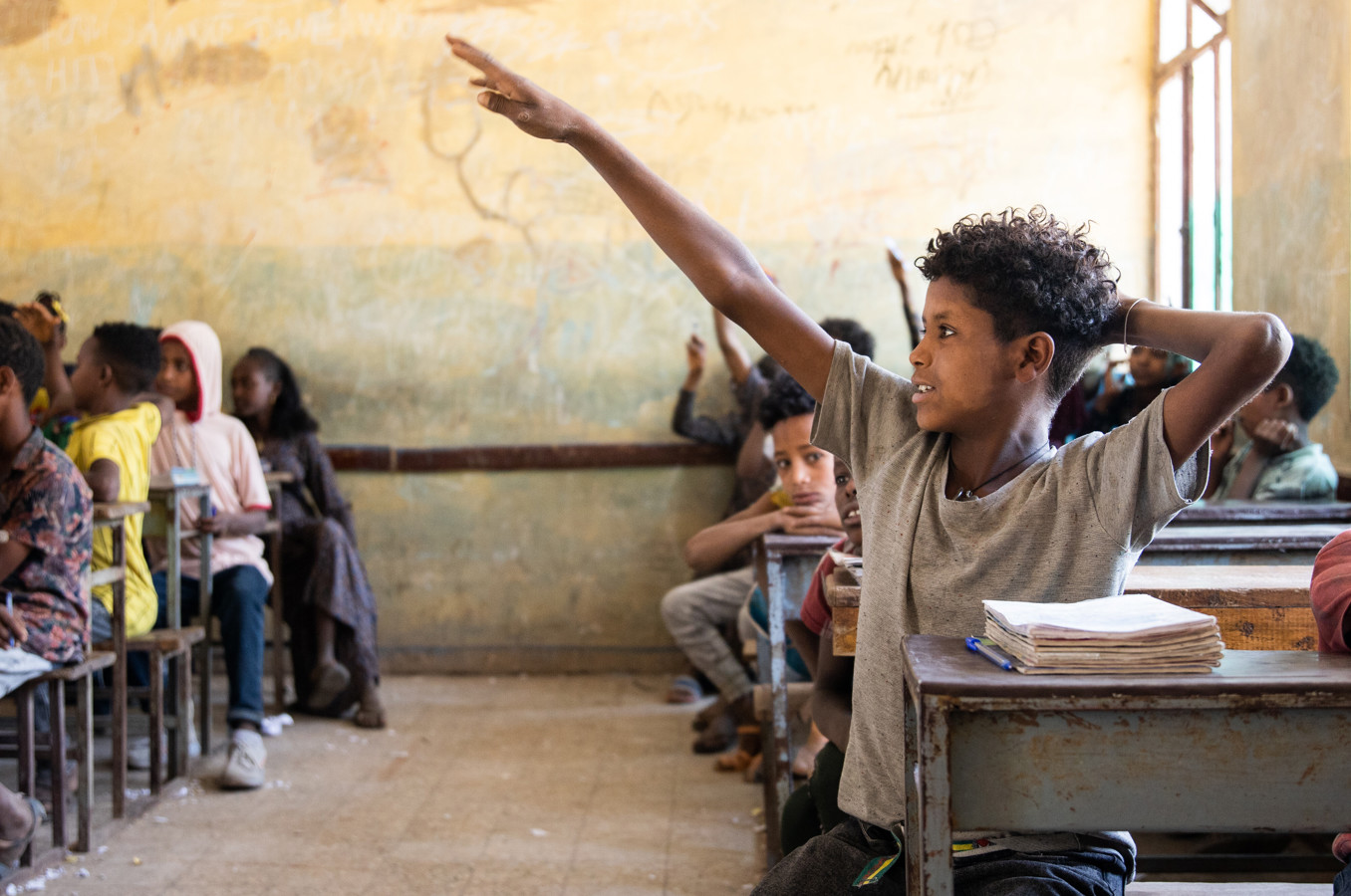 A young boy raises his hand in a classroom in Ethiopia.