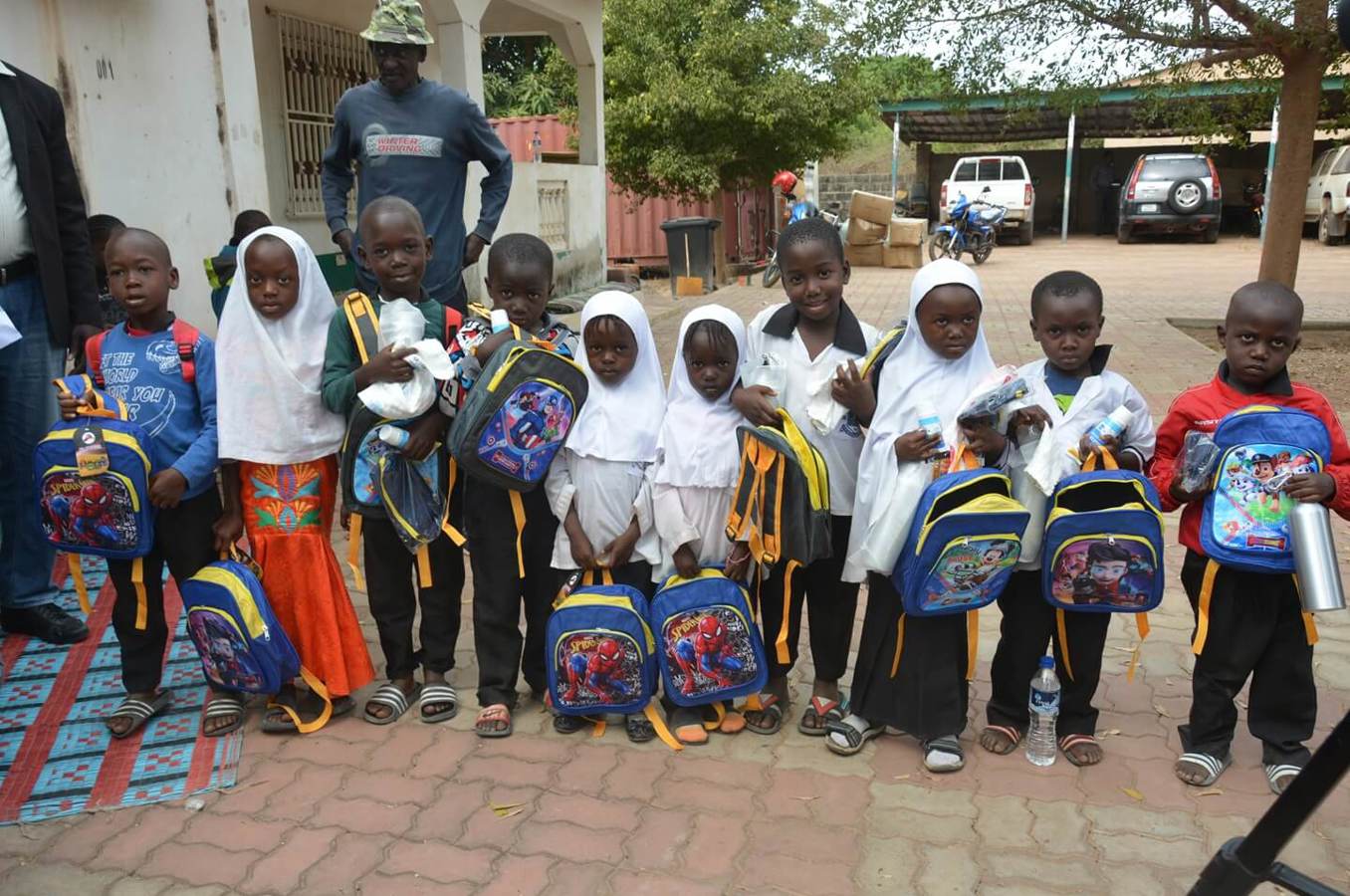 Children in The Gambia stand with the new backpacks they received.
